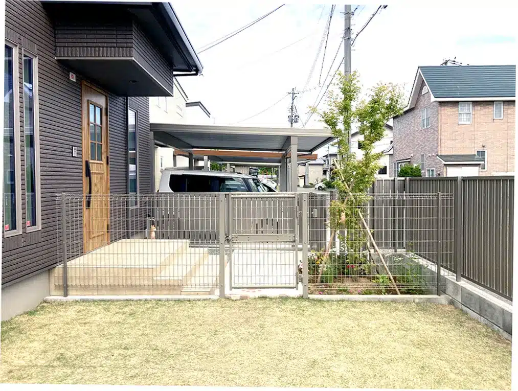 家屋とカーポート、そしてドッグランへの二重扉がある外構