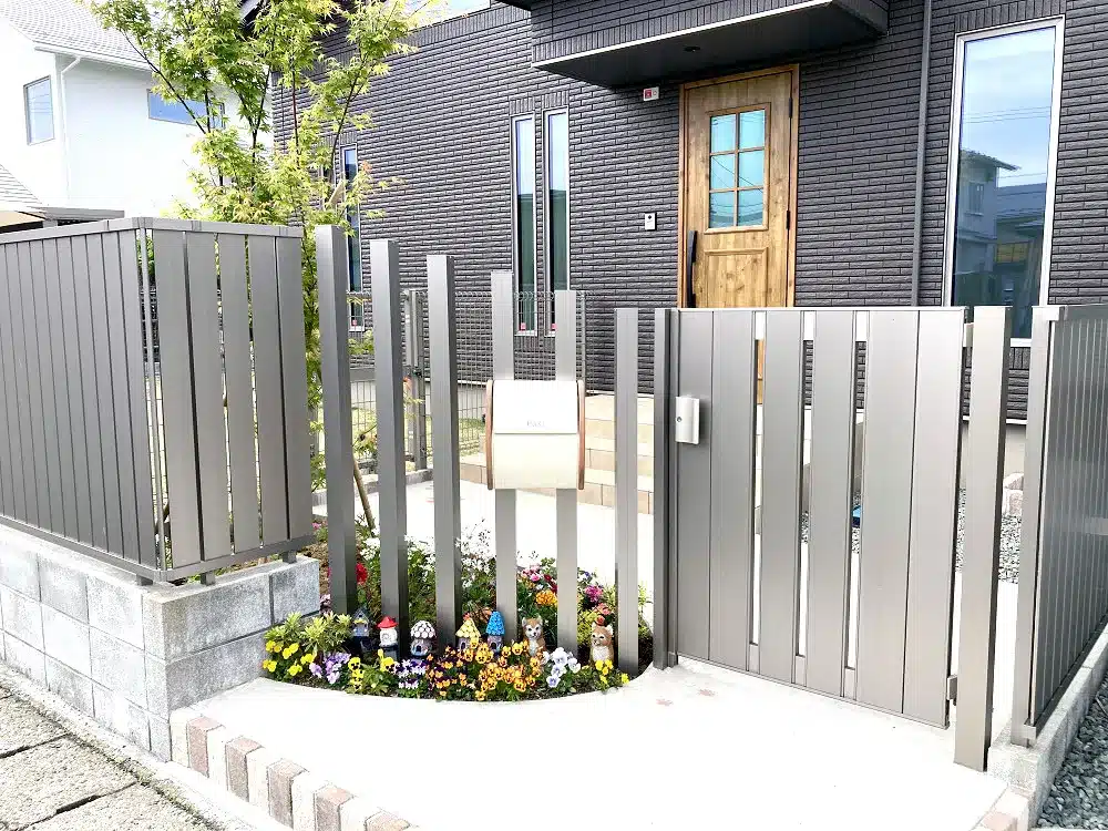 門扉と郵便受け、色とりどりの花々が植えられた玄関アプローチ
