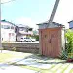 秋田市W様邸の、デザイン物置と枕木風のアプローチ、広がる開放的な庭の風景。