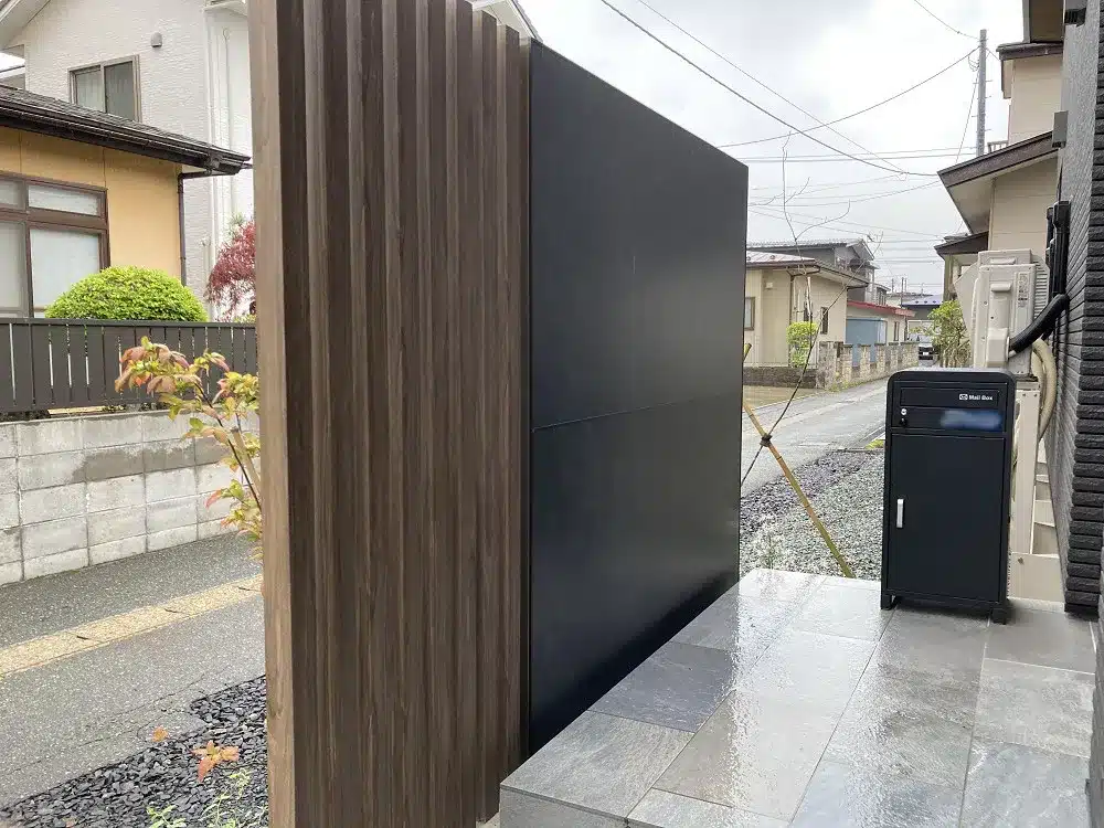 秋田の住宅玄関アプローチの入り口付近。シックな目隠し、機能的なポスト、そして屋外用宅配ボックス。