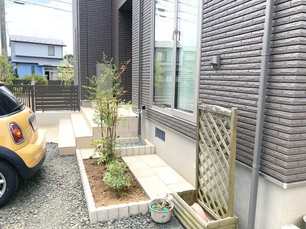 植栽が植えられた花壇と、隣接する飛び石と調和したデザインの荷物運び込み用足場。