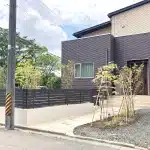 道路側から見た秋田市K様邸の外構全景。弾性塗装された擁壁とアルミフェンスが印象的なリフォーム事例。