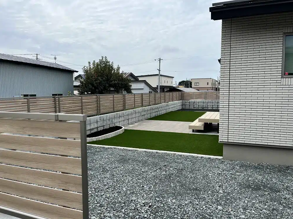 大館市S様邸の木調フェンスで囲われた人工芝と平板テラスのあるお庭。